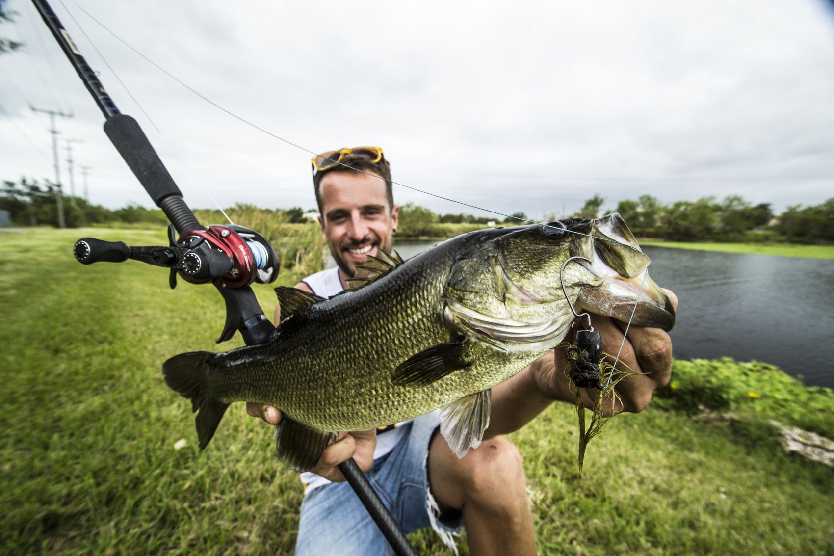 Angler holding a bass with fishing tackle visible